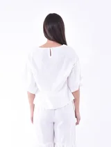 Blusa negra de mangas cortas con volados y escote redondo.