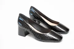 Zapato de salón negro con textura grabada, tacón cuadrado de 5 cm y puntera ligeramente cuadrada y redondeada.