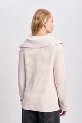 Buzo de punto color crudo con cuello polo y aberturas laterales.