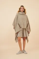 Poncho de lana color marrón con cuello alto, mangas 3/4 y bolsillo lateral con detalle de botones de cuero.