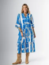 Vestido midi de corte amplio con estampado abstracto en tonos azules, blancos y beige. Tiene cuello en V, mangas 3/4 con volados y corte escalonado en la falda.