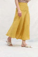 Falda midi color mostaza, de lino, con corte evasé y cintura alta.