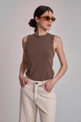Musculosa marrón de tejido liso, con cuello redondo y tachas metálicas decorativas en los hombros.