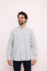 Camisa celeste con rayas verticales blancas, de corte clásico, con cuello abotonado, manga larga y bolsillo en el pecho.