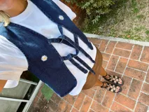 Chaleco de denim azul con cuello en V y cierre con lazos. Decorado con margaritas bordadas.