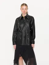 Camisa negra de cuero ovino con broches forrados en el mismo cuero, remaches con brillo en el delantero y cuello, y bolsillos con vista de cuero en el delantero.