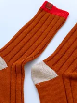 Par de medias acanaladas color ladrillo con puntera y talón en color crema y puño superior en color rojo.