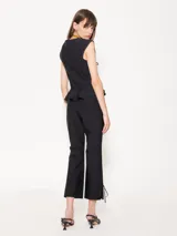 Pantalón negro con cintura rebatida y cierre lateral. Diseño entallado con pinzas delanteras y traseras, corte flare y tajo en el ruedo con moño.