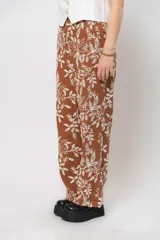 Pantalón de corte recto color marrón con bordado floral blanco.