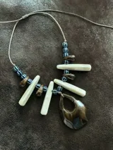 Collar largo con tiento sintético ajustable, cuentas de cerámica y medallones grandes de resina color marrón, blanco y azul.