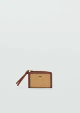 Billetera pequeña color beige con textura de rafia y borde de cuero marrón. Tiene cierre metálico a presión, logo en relieve, seis ranuras para tarjetas y cierre de cremallera.