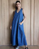 Vestido largo color crudo, sin mangas y con escote en V. Presenta aberturas laterales en el ruedo y bolsillos laterales a la altura de la cadera.