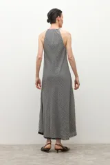 Vestido largo de tirantes finos, con escote en V decorado con encaje negro. El tejido presenta un estampado de cuadros vichy en blanco y negro.