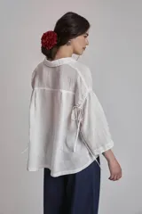 Camisa blanca de lino con cuello clásico, cierre frontal con botones y mangas 3/4 abullonadas.