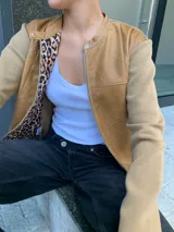 Campera marrón con cuerpo de cuero y mangas de lana color beige. Interior con estampado animal print. Corte clásico con cuello redondo y cierre frontal con botones a presión.