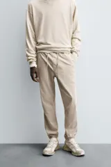 Pantalón jogger negro de corte slim fit, confeccionado en tejido de algodón con cintura elástica ajustable con cordón, bolsillos frontales y traseros de vivo, y bajo con puño elástico.