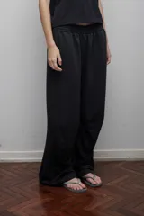 Pantalón negro de algodón con pretina elástica, bolsillos laterales y pinzas horizontales en las rodillas.