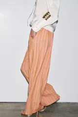 Pantalón de pierna ancha confeccionado en mezcla de lino a rayas verticales color rosa y beige. Tiene tiro medio, cintura elástica y bolsillos delanteros.