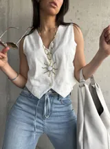 Chaleco blanco con bordado broderie, escote en V y cierre frontal con botones.