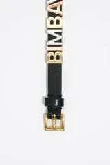 Pulsera de cuero negro con letras metálicas tricolor con el nombre de la marca. Cierre con hebilla metálica dorada y logo grabado.