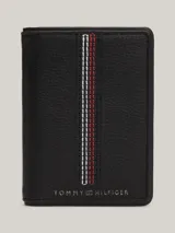 Billetera plegable Tommy Hilfiger de cuero negro con sutil acabado granulado. Presenta costuras distintivas en rojo, blanco y azul en el frente y logo de la marca en la parte inferior.