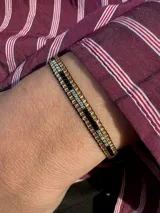 Pulsera tejida con canutillos plateados, dorados y negros.
