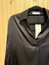 Blusa azul petróleo de seda con cuello clásico y corte asimétrico, más larga en la parte trasera.