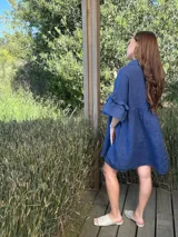 Vestido camisero azul de lino italiano, con cuello camisero, botones frontales, mangas 3/4 con doble volado y bolsillos laterales.