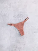 Bottom de bikini colaless color salmón con textura acanalada. Presenta reguladores ajustables en los laterales con hebillas metálicas.