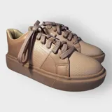 Championes negros de cuero sintético con textura tipo piel de reptil, cordones anchos y suela plana.
