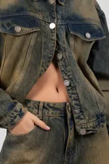 Campera de jean azul con lavado matizado, corte regular, acceso con botones personalizados, bolsillos delanteros con tapa y bolsillos laterales funcionales. Cada prenda es elaborada de manera artesanal, lo que las distingue unas de otras. Los tonos en el lavado pueden variar desde claros hasta oscuros.