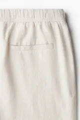 Pantalón color crema de corte ancho, con cintura elástica ajustable con cordón. Confeccionado en tejido de mezcla de lino y viscosa.