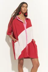 Túnica corta de mangas cortas con cuello camisero y cierre frontal con botones. Presenta un diseño bicolor con una franja diagonal en color beige.