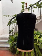 Chaleco negro tejido a mano en dos agujas con hilado 100% baby alpaca, ligeramente oversize, de hombros anchos y cuello tipo bote, con puntos calados en frente y espalda y tajos a los lados en el bajo.