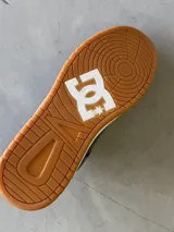 Championes DC modelo Sarah, color gris oscuro con detalles en blanco y suela de goma color caramelo. Presentan el logo de DC en blanco en el lateral y están inspirados en la cultura skate.