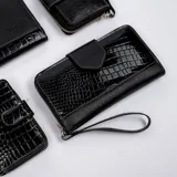 Billetera dorada con cierre metálico y solapa con el logo de la marca Vanitas. Tiene múltiples compartimentos para tarjetas y billetes. Incluye correa de muñeca extraíble.