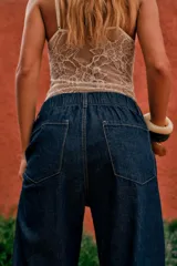 Pantalón denim fino color marrón, de corte amplio y tiro alto, con elástico en la parte trasera de la cintura y lazo ajustable.