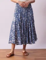 Falda midi de algodón estampada con flores blancas sobre fondo azul. Tiene pretina ancha elastizada en punto smock, ruedo con volados y forro interno a tono.