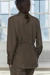 Camisa marrón de Zara Woman Collection, confeccionada en hilatura con viscosa. Tiene cuello solapa, manga larga con puño, bolsillo de plastrón en el pecho, cinturón ajustable con lazadas y bajo asimétrico. Se cierra con botones frontales.