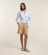 Blusa celeste a rayas verticales, de tricolina, con escote en pico cruzado, lazo lateral, mangas largas y cuello solapa.