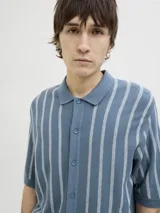 Polo de punto azul con rayas verticales blancas, cuello tipo camisa, cierre con botones y mangas cortas.