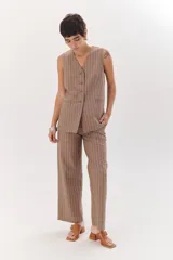 Chaleco gris con finas rayas verticales blancas, con cuello en V, cierre frontal con botones y bolsillos laterales.