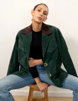 Blazer verde pino de gamuza con cuello marrón chocolate, bolsillos con solapa y botones color hueso.