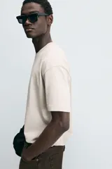 Camiseta blanca de algodón compacto, corte relaxed fit, cuello redondo y mangas cortas.