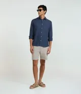 Camisa marrón claro de lino, de corte clásico, con cuello inglés, manga larga y cierre frontal con botones blancos.