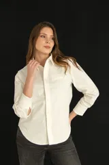 Camisa blanca de corte clásico con bolsillo en el pecho, mangas largas y botones al tono.