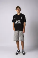 Remera tejida color crudo con cuello tipo chomba en V, mangas cortas con rayas negras y estampado con letras en el frente. Confeccionada en hilado de algodón.