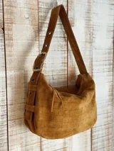 Bolso de hombro marrón de gamuza con diseño de cuadrícula en relieve, correa regulable con hebilla y cierre superior.