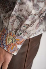 Camisa oversize de mangas largas con puños abotonados, cuello clásico y cierre frontal con botones. Estampado con motivos paisley en tonos pastel.