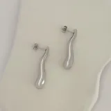 Aros colgantes plateados con forma de gota irregular.